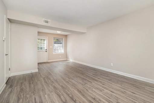 A room with light wood flooring and white walls.