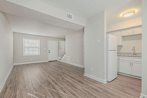 A spacious room with wooden flooring and white walls.