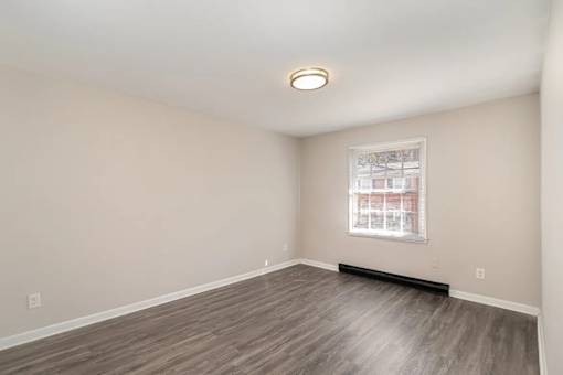 A room with a window and a wooden floor.