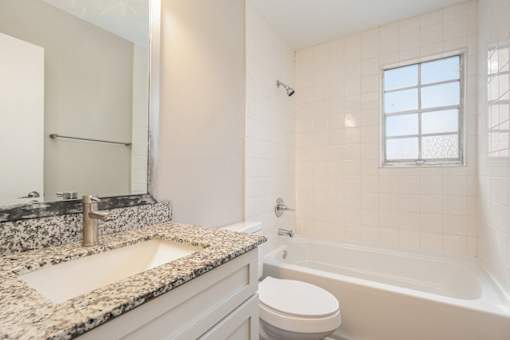 A bathroom with a marble countertop and a white toilet.