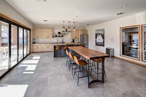 A modern kitchen with a long wooden table and chairs.