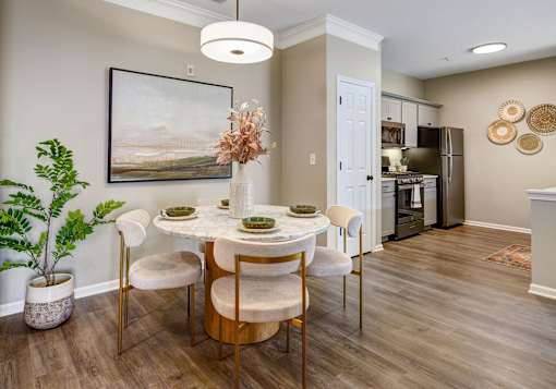 A dining room with a table set for four and a painting on the wall.