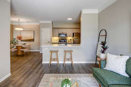 A living room with a green couch and a kitchen area in the background.