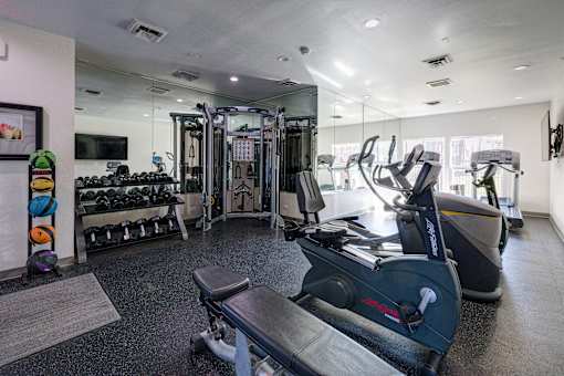 A gym with a variety of equipment including treadmills, weights, and exercise machines.