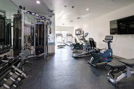 A spacious gym with a variety of equipment including treadmills, elliptical machines, and weight machines.