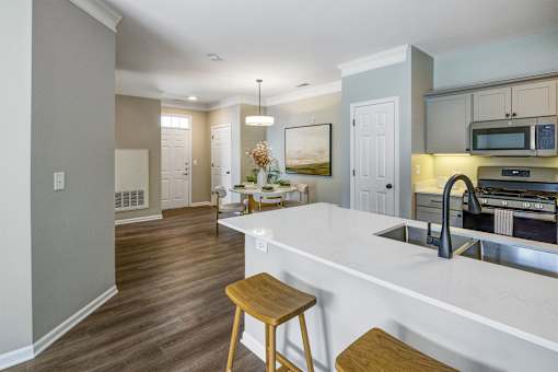 A kitchen with a white counter top and wooden stools.