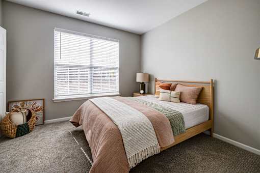 A bedroom with a bed, pillows, and a basket on the floor.