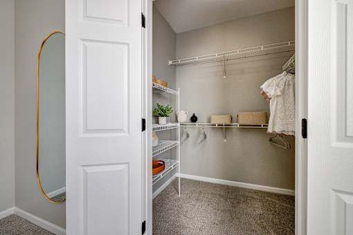 A white closet with clothes hanging and shelves.