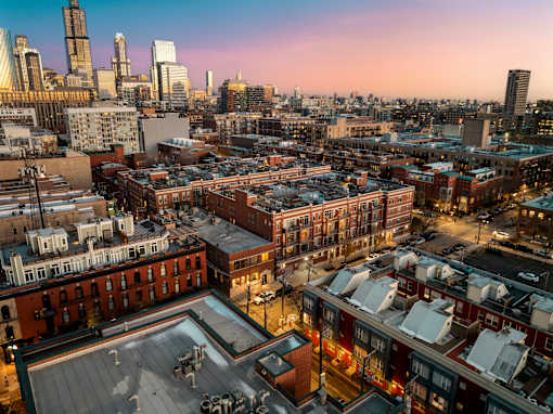 A cityscape with buildings and a parking lot in the foreground.