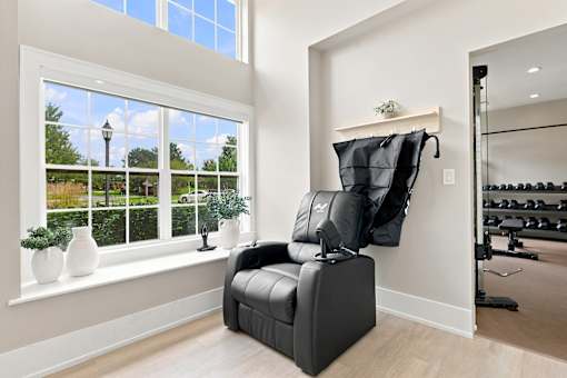 A black chair is in front of a window in a room with a gym in the background.