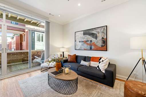 A living room with a grey couch, a coffee table, and a painting on the wall.