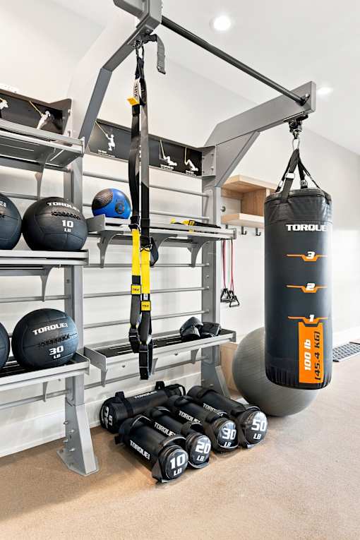 A gym with a punching bag, weights and a bench.