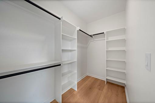 A white closet with shelves and a black rail.