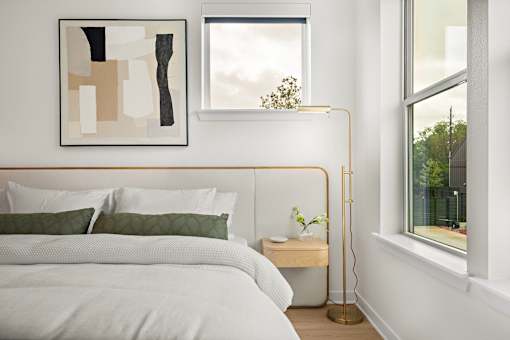 A bedroom with a white bed and a painting on the wall.