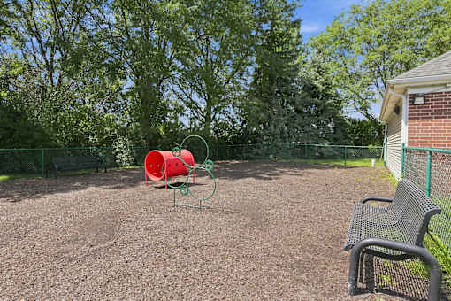 A playground with a red bucket and a green swing set.