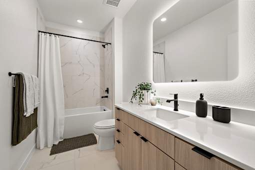 A modern bathroom with a marble patterned shower and a white toilet.