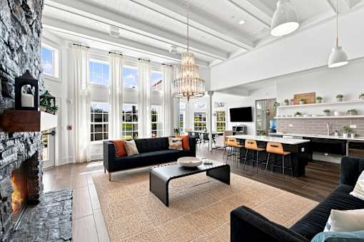A modern living room with a stone fireplace and a black couch.