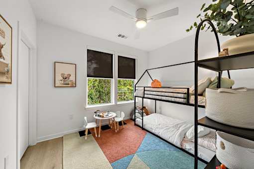 A room with a bunk bed and a table with chairs.