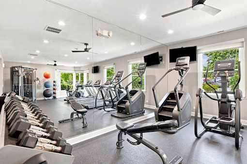 A spacious gym with a variety of equipment including treadmills, stationary bikes, and weight machines.