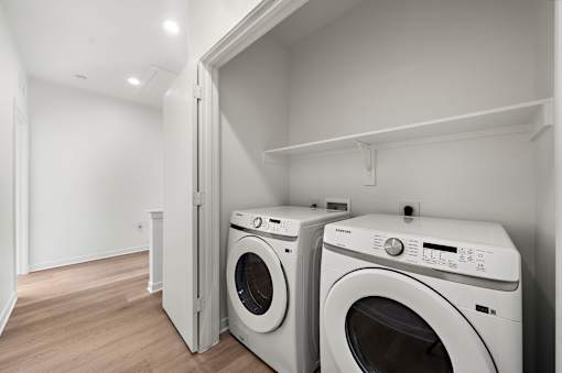 Two white front loading washing machines in a laundry room.