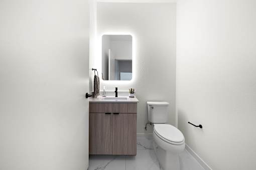 A white bathroom with a toilet, sink, and mirror.