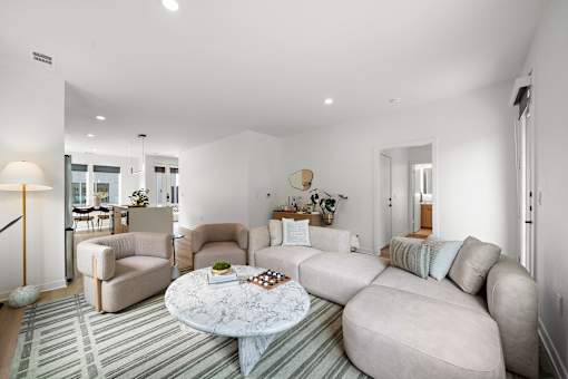 A living room with a grey sofa, a white coffee table, and a striped rug.