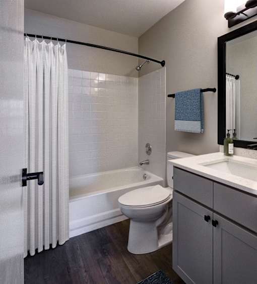 A white toilet sits in a bathroom next to a bathtub.