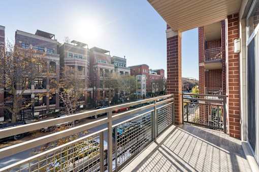 A balcony with a metal railing overlooks a city street.