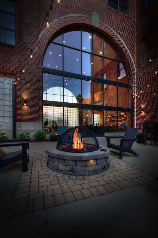 A fire pit sits in the middle of a brick courtyard.