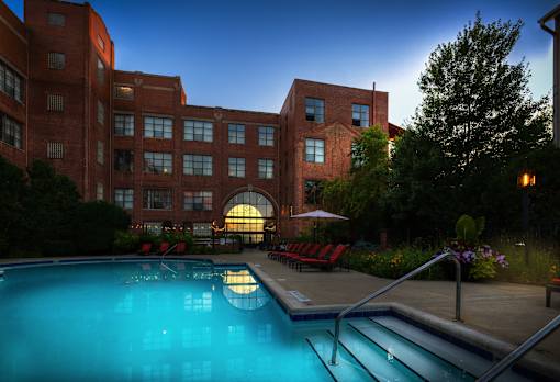 A large red brick building with a pool in front.