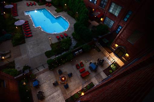 A pool surrounded by red chairs and umbrellas.