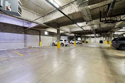 A parking garage with concrete floors and yellow poles.