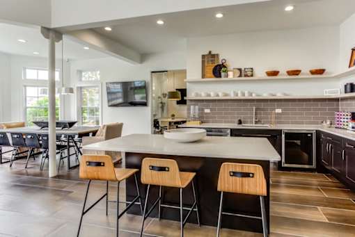 a kitchen with a center island and chairs in front of a table