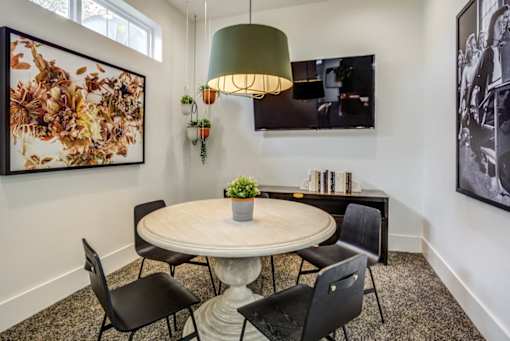 a dining room with a round table and chairs and a tv on the wall