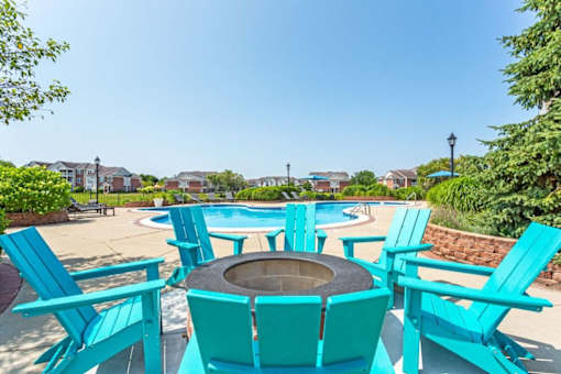 a patio with turquoise chairs and a fire pit