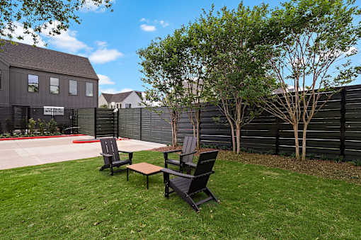 A backyard with a black fence and two black chairs.