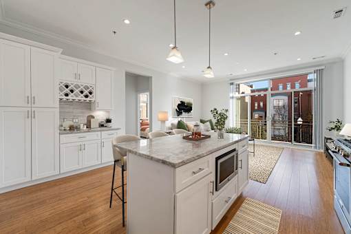 A modern kitchen with white cabinets and a marble island.