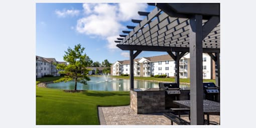 A patio with a table and chairs overlooks a pool and apartment buildings.