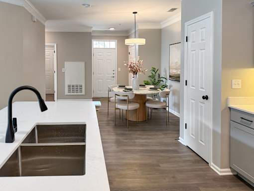 A kitchen with a sink and a dining table with chairs.