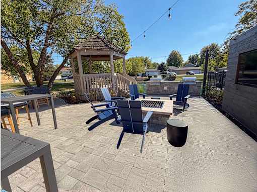 A patio with a gazebo, chairs, and a table.