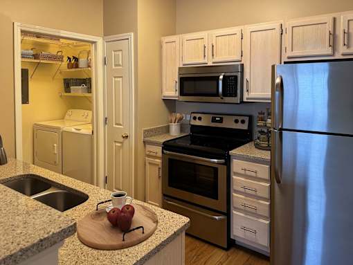 A kitchen with a refrigerator, oven, and sink.