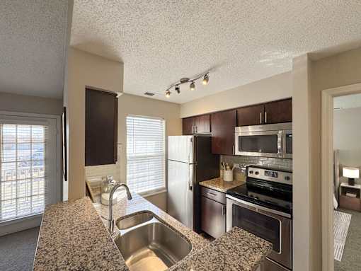 A kitchen with a sink, stove, and refrigerator.