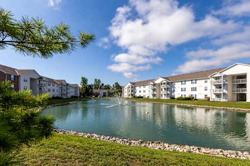 A pond in front of apartment buildings on a sunny day.