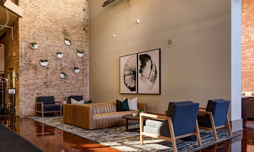 a lobby with a couch and chairs and a brick wall