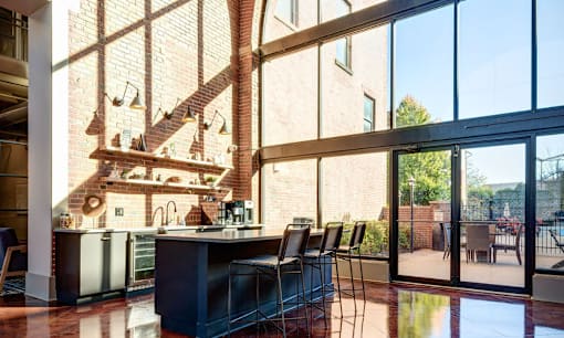 a living room with large windows and a bar with chairs