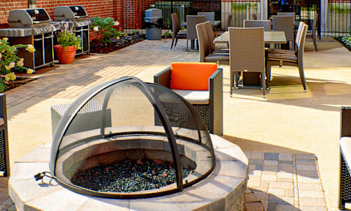 a fire pit on a patio with chairs and tables