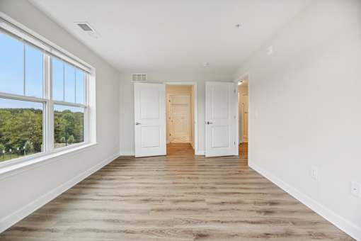 A room with white walls and wooden flooring with two white doors.