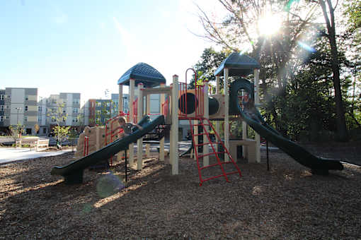 A playground with a green slide and a red ladder.