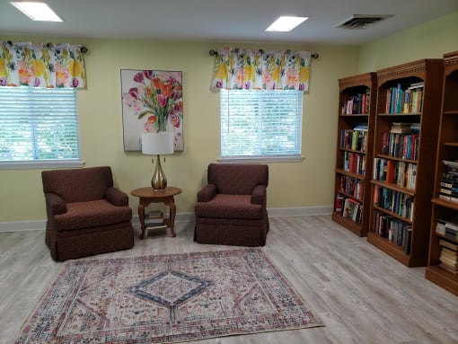 a sitting area with two chairs and a table with a lamp
