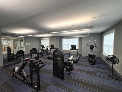 A gym with a variety of equipment including treadmills, stationary bikes, and elliptical machines.